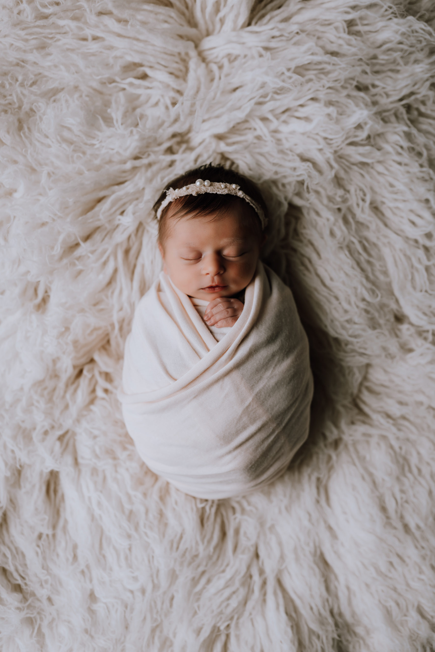 newborn baby in wrapped in white on fur rug Kitchener Baby Stores